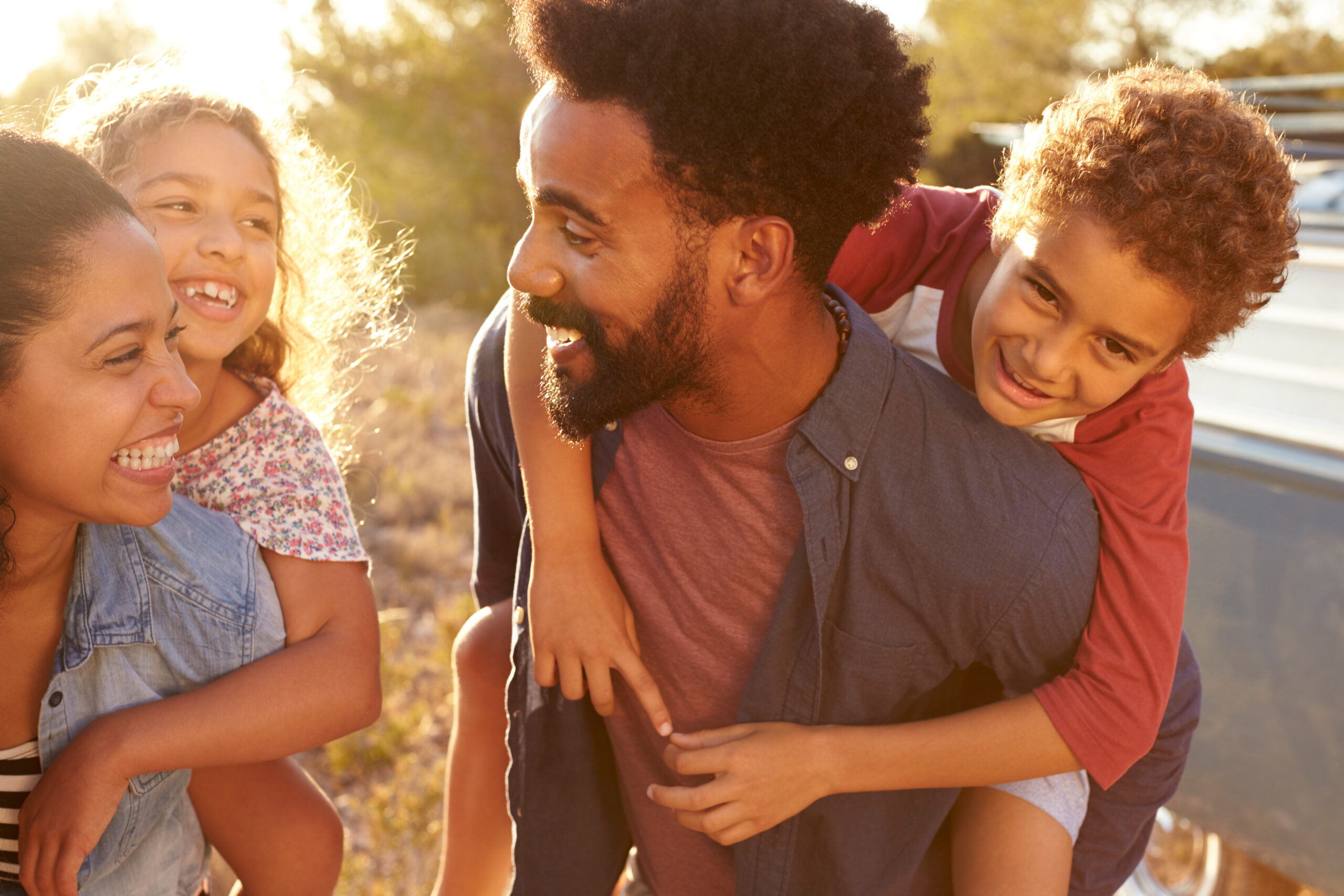 Foster Carers with two children on their bags smile lovingly at one another