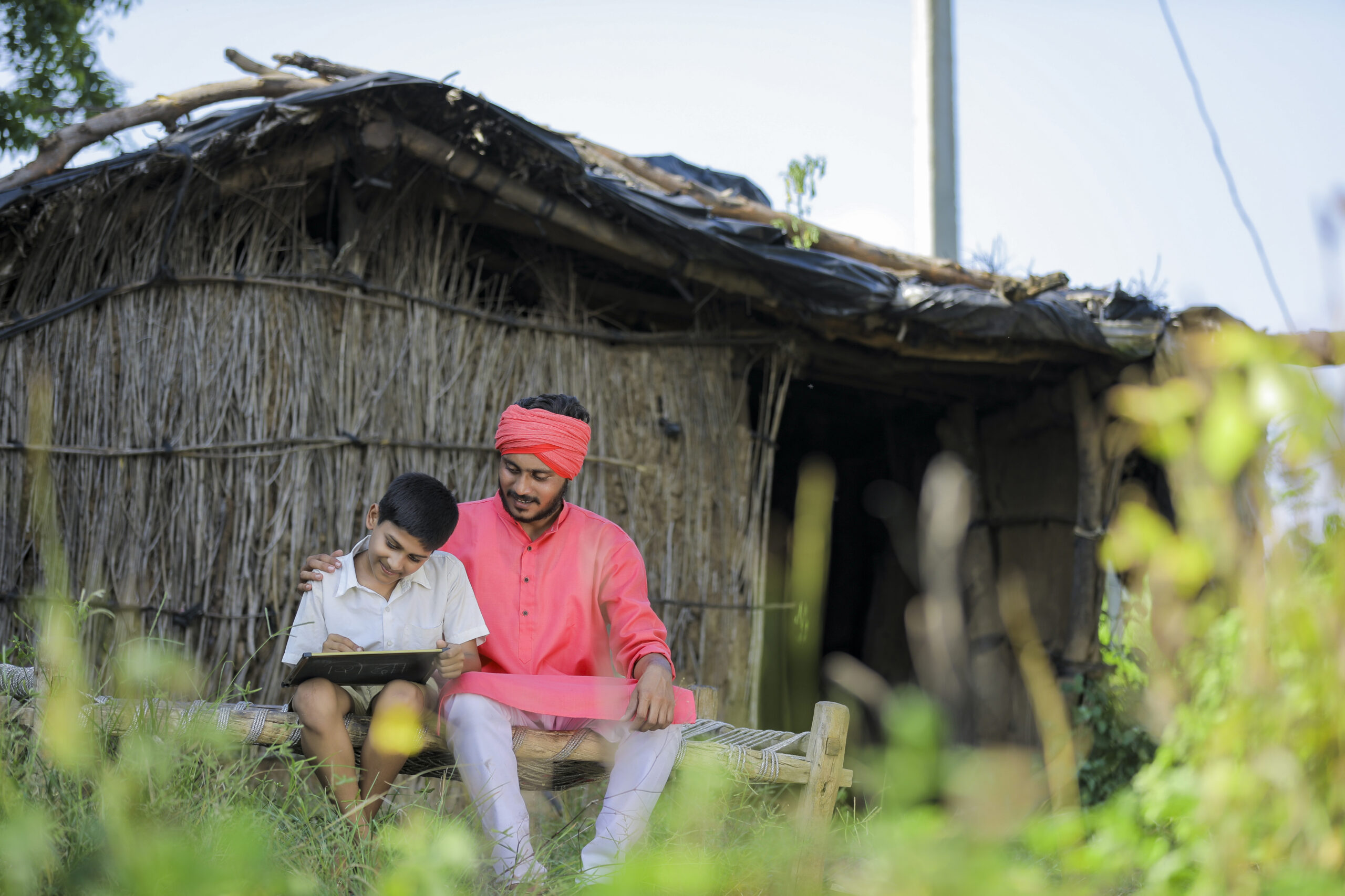 Parent sitting with child outside of a house as child writes