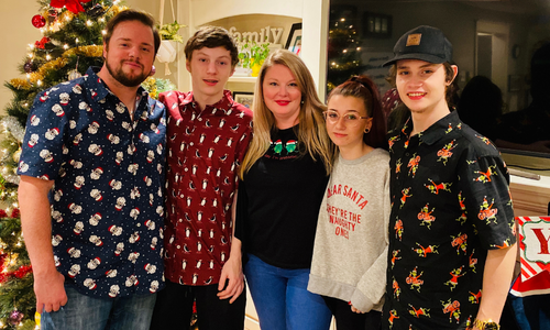 Foster Family stand together in front of Christmas Tree