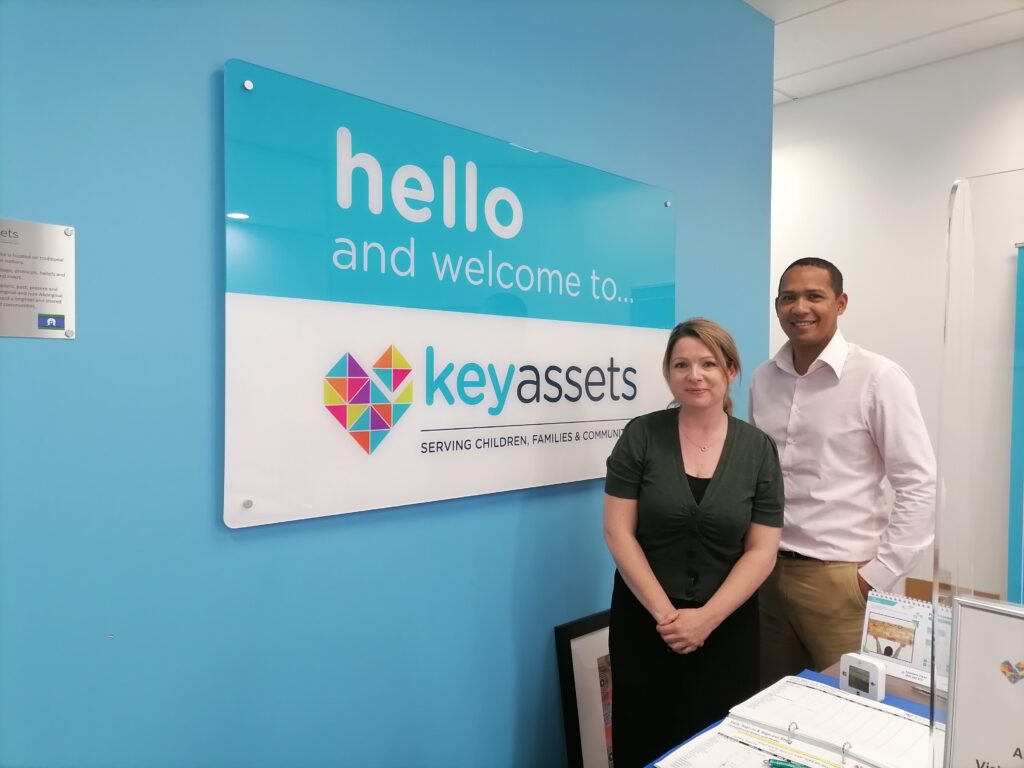 Two people standing in front of the Key Assets Australia welcome sign in Australia