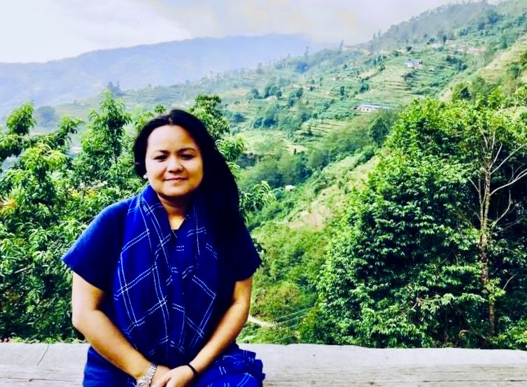 Anju Pun sitting in front of lucious greenery with moutains in the distance