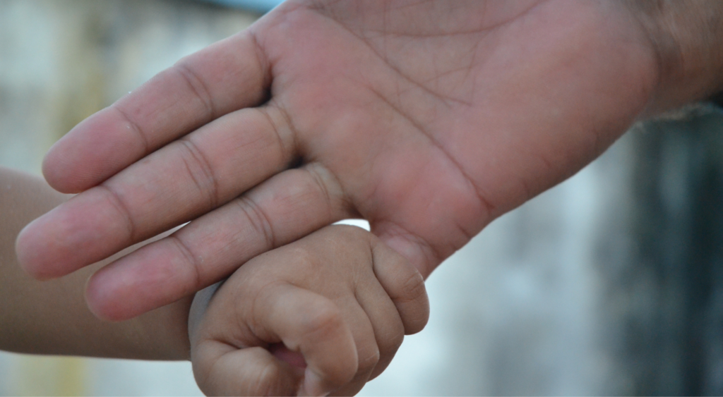 A baby holds the hand of its parent in Nepal. Parenthood.<br />
